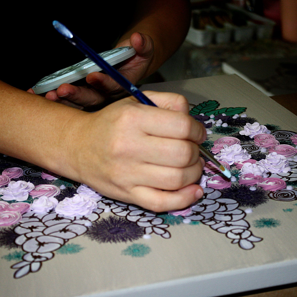 Close up of artist sculpting 3d flowers onto a canvas painting