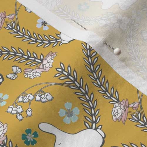 Close up of fabric with goldenrod yellow woodland bunnies and flowers